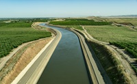 The aerial view looks south over the California Aqueduct and agricultural fields, near Interstate 5 and the Delta-Mendota Canal in Stanislaus County, California. The aqueduct is a critical part of the State Water Project that carries water from the Sacramento-San Joaquin Delta to the San Joaquin Valley and Southern California. Photo taken May 13, 2023.