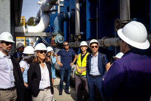 Multiple people wearing hardhats looking toward a person speaking.
