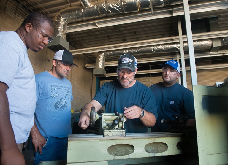 Utility Craftsworker apprentices at the DWR Operations and Maintenance Training Center learn from instructor how a lathe machine shapes and cuts metal. 