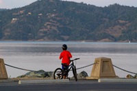 A young bicyclist takes in the view at dusk from the top of Oroville Dam in Butte County, California. Photo taken July 26, 2019.