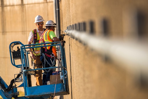 Workers from Bullert Industrial Electric install 2-inch metal conduit piping to carry optical fiber on the front side of the Lake Oroville main spillway. 
