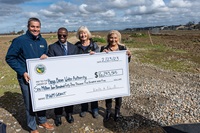California Natural Resources Agency Secretary Wade Crowfoot, left, Steve Doe, Special Investigations Branch Manager, DWR, Mary Fast – Kings Water Authority Board Chair, and Alma Beltran, Mayor of Parlier, are seen at this event posing with this check presented to them by DWR in front of other local officials from across the Central Valley, in Parlier, at the Foothill Basin Project Site, some of which is seen behind the fence in the background, before $15 million in financial assistance from DWR’s Integrated Regional Water Management (IRWM) Program was presented. 