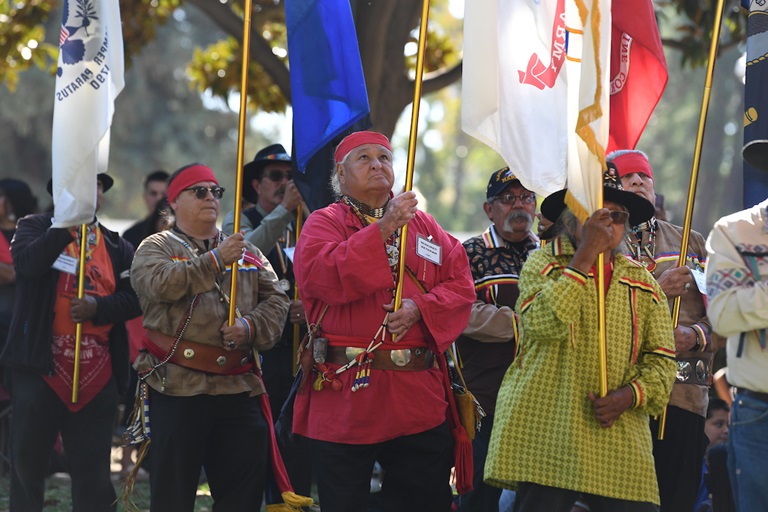 Tribal representatives carrying flags during the grand entry and posting of colors during California Native American Day