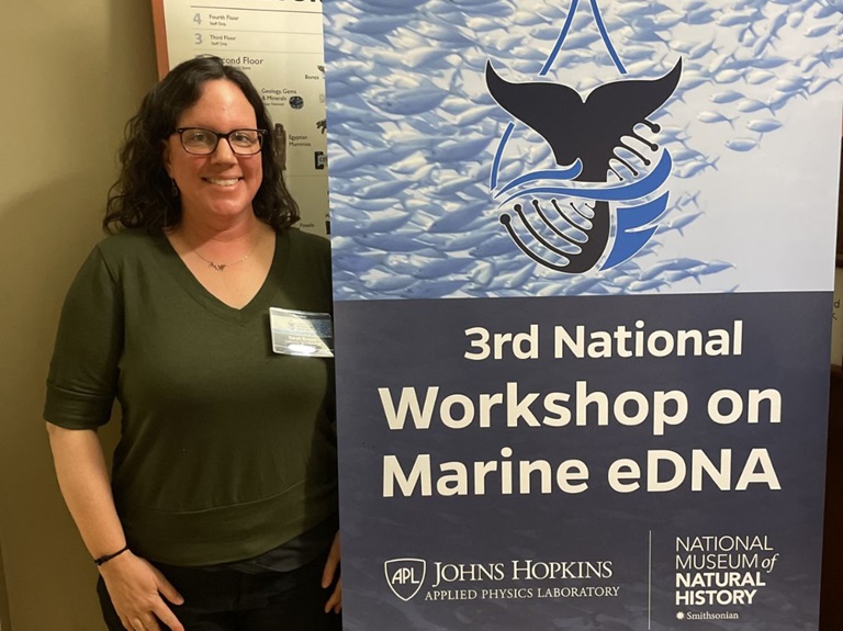 DWR senior environmental scientist Sarah Brown standing next to the banner for her workshop on Marine eDNA in Washington D.C.