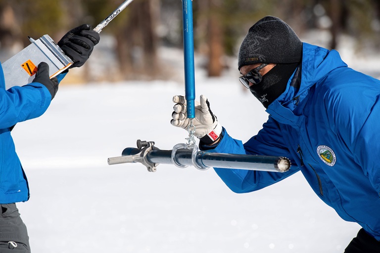 Sean de Guzman (right), chief of the California Department of Water Resources Snow Surveys and Water Supply Forecasting Section, conducts the first media snow survey of the 2021 season at Phillips Station in the Sierra Nevada Mountains.