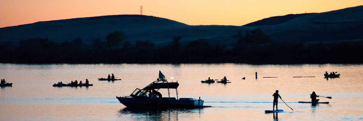 Boats, kayaks, and paddleboarders on Lake Oroville at sunset