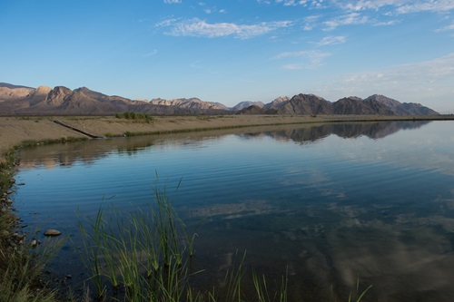 A recharge pond with mountains in the background