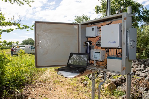 Digital stream gage with laptop and notebook in foreground